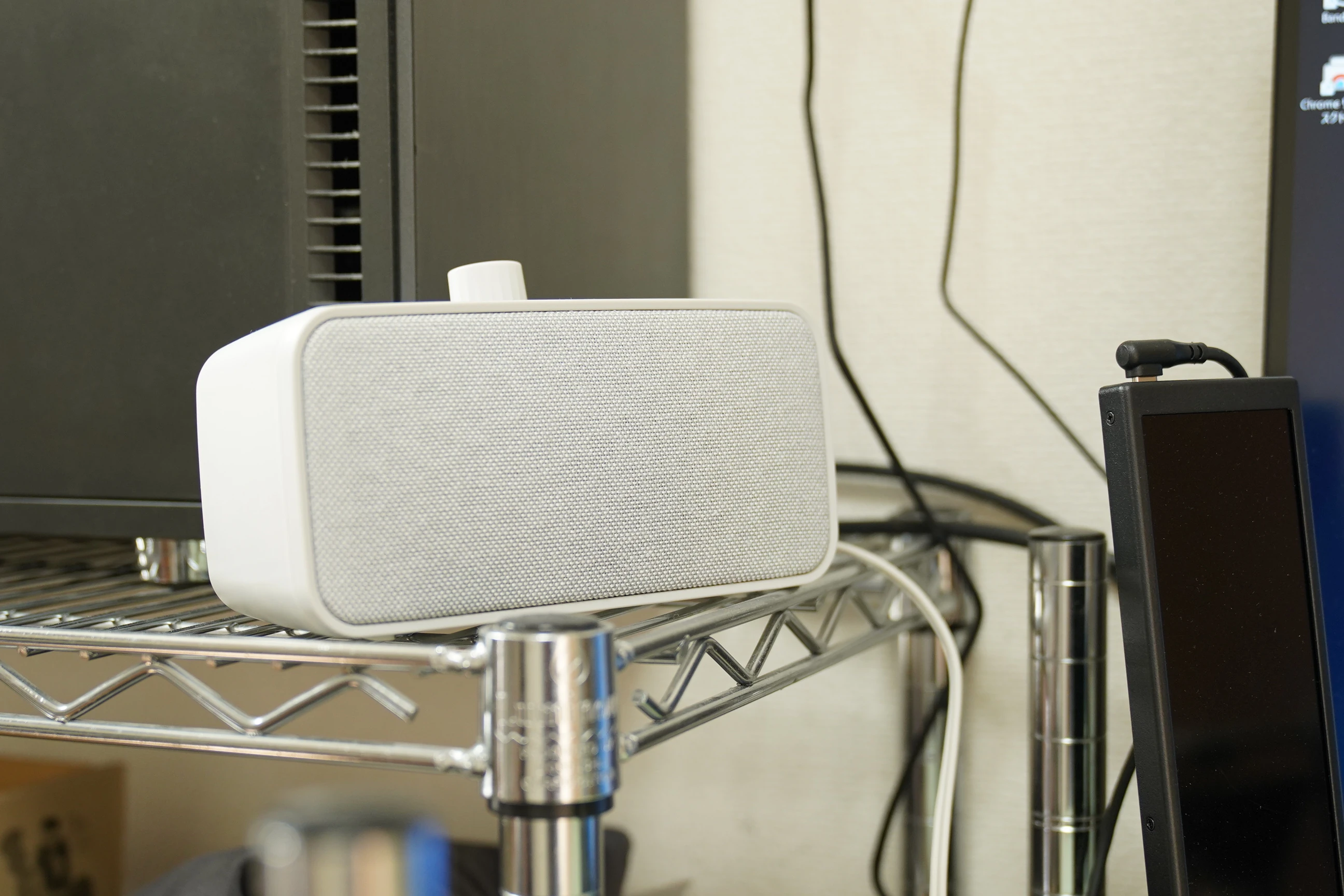 Speaker on a shelf beside the desk; its integrated body fits conveniently into an available space